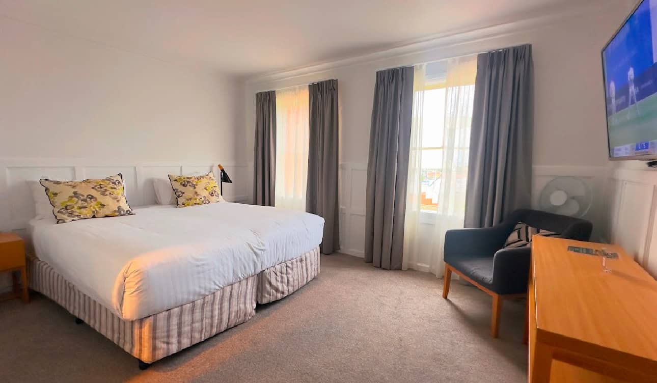 Rydges Hobart Room: A spacious hotel room with a plush bed, wooden furniture, and soft lighting