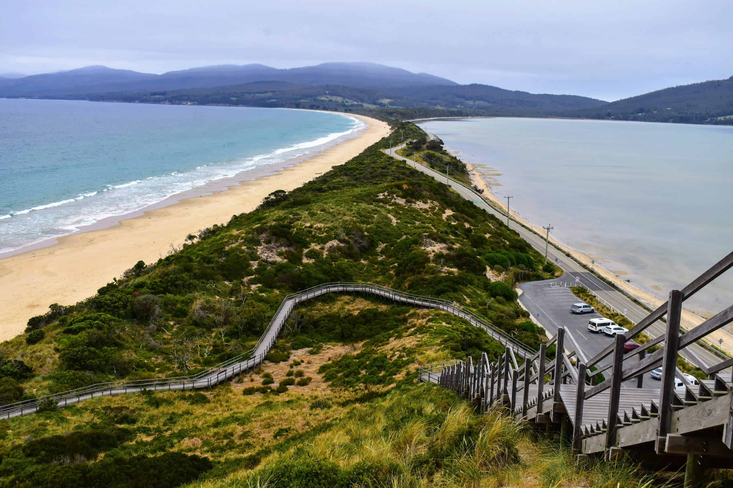 A panoramic shot of The Neck, a narrow isthmus connecting North and South Bruny, with a wooden staircase leading to a stunning viewpoint.