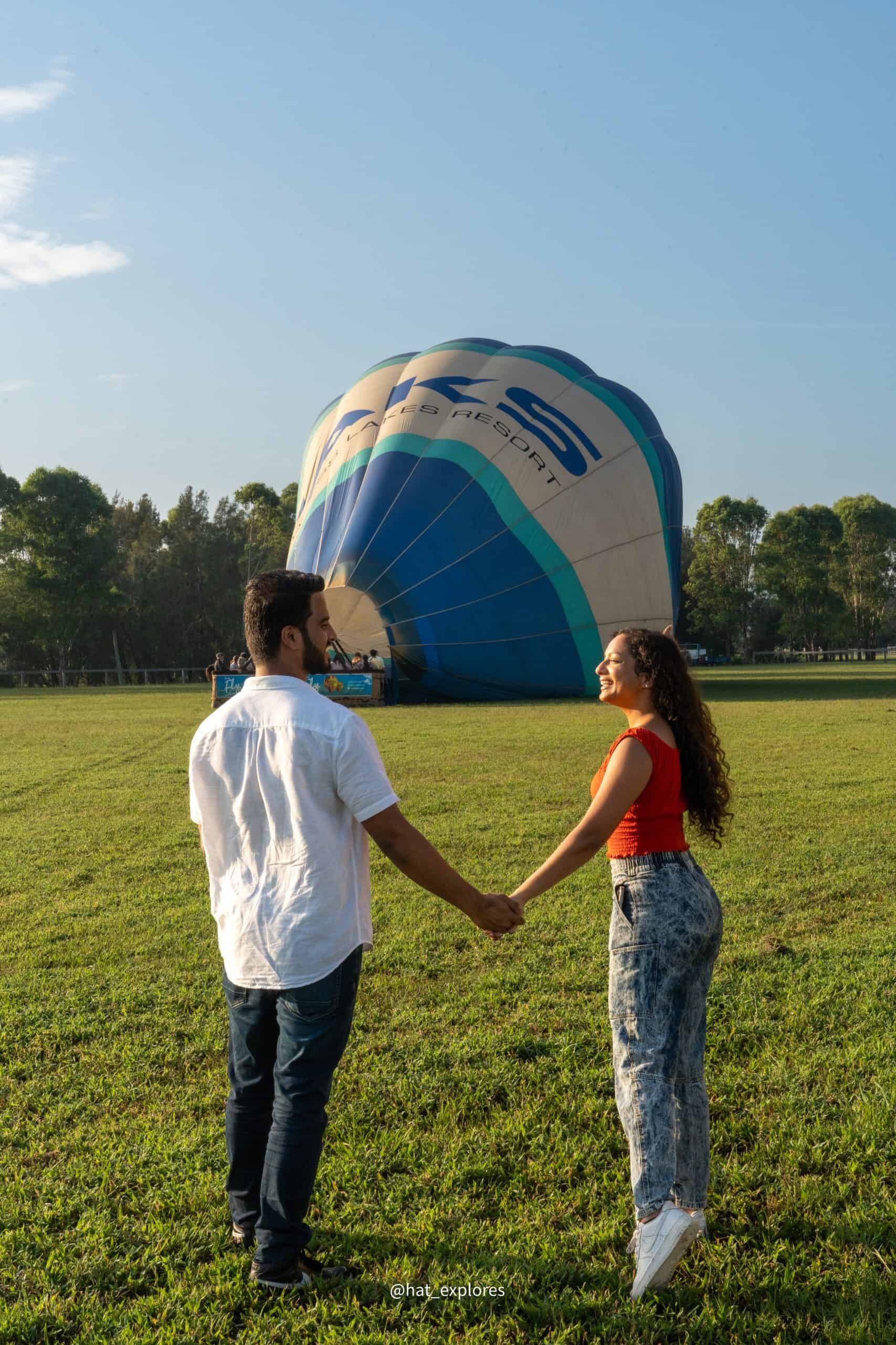 A man in a white shirt looking at a girl who is smiling and pointing  towards their hot air balloon ride in Sydney.