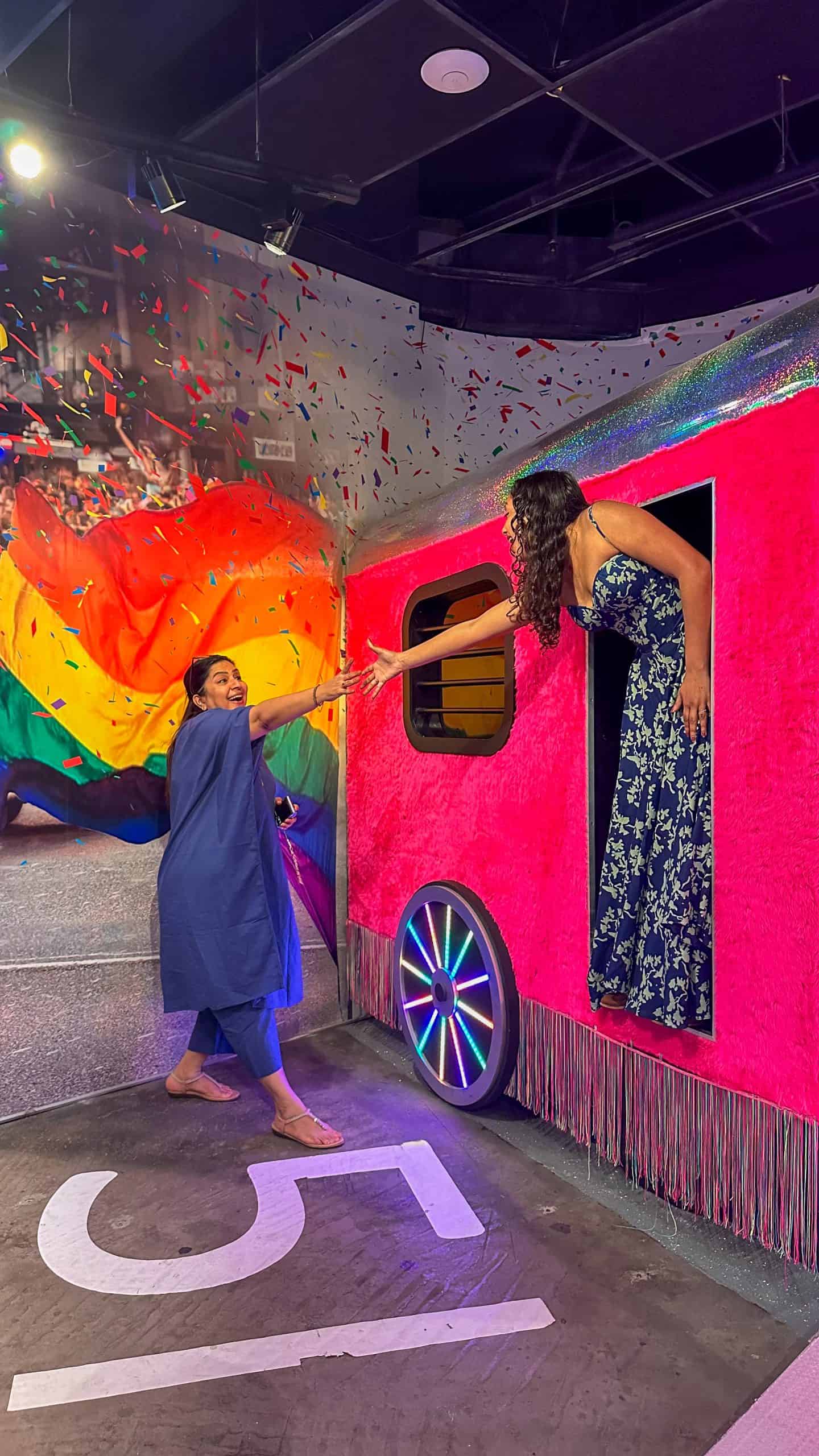 One women in a blue floral dress is reaching out to another women from a train setup at Madame Tussauds, making it a great outing with the family in Sydney!