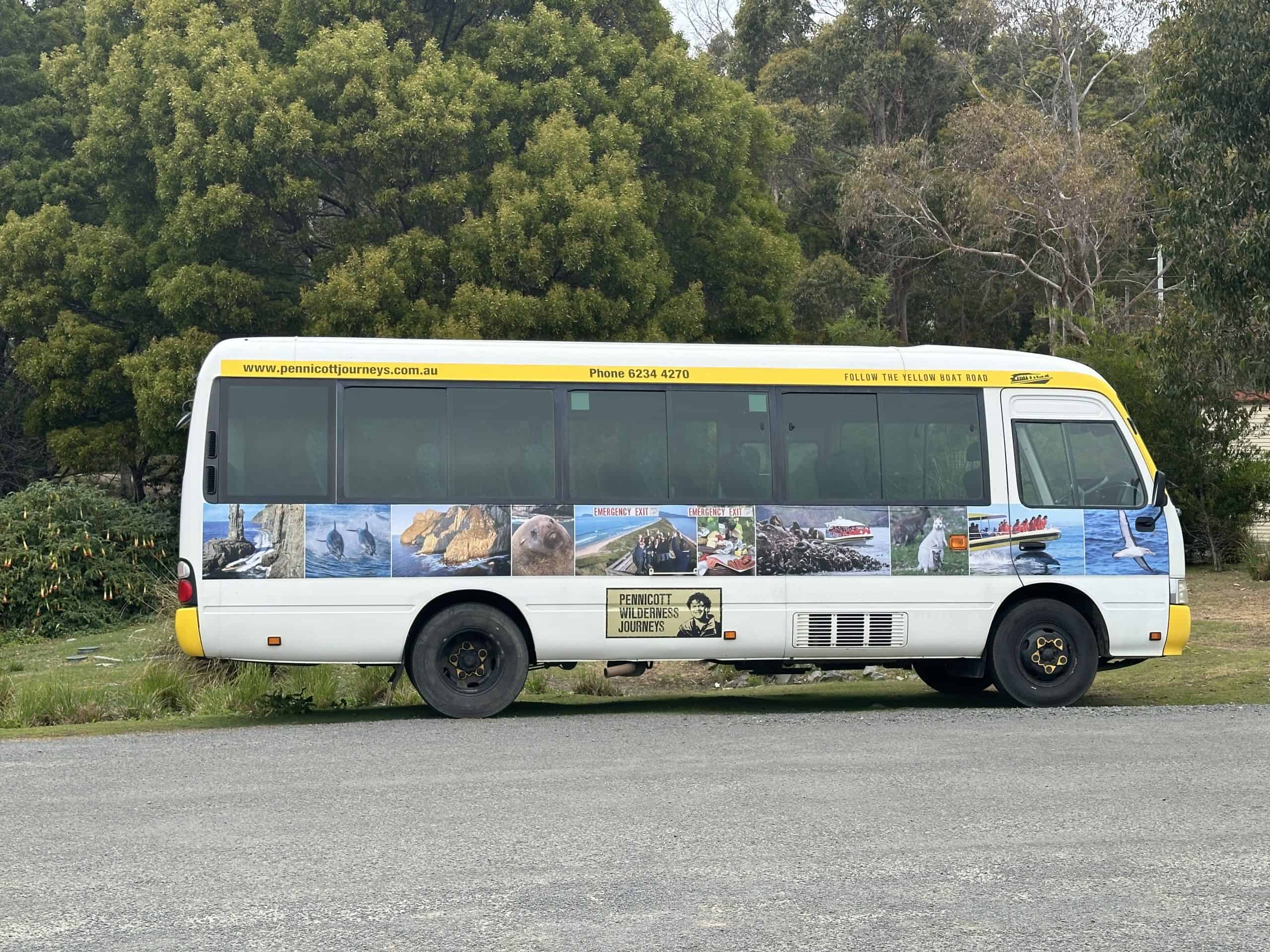 Bright yellow Pennicott Wilderness Journeys tour bus picking up passengers from Hobart for a full day Bruny Island tour.