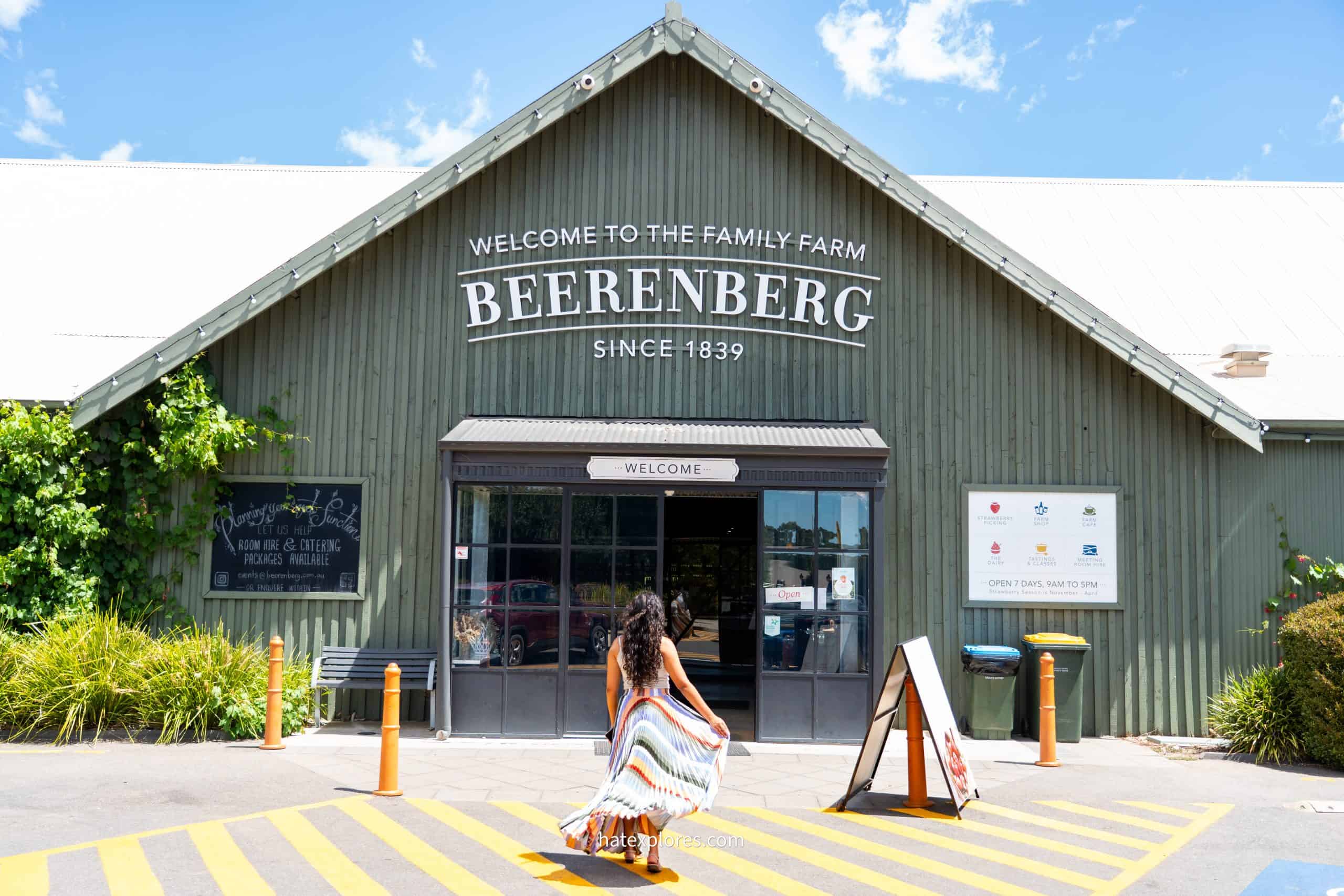 A woman in a colorful striped dress walks toward the entrance of Beerenberg Farm, a historic family-owned attraction since 1839—perfect for a local food experience on a 3-day Adelaide itinerary.

