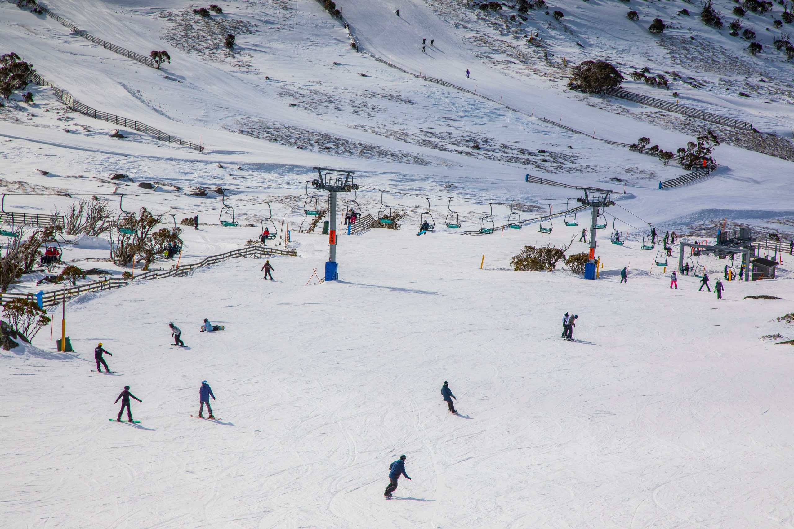 People enjoying a day of skiing and snowboarding at Blue Cow ski resort in Perisher.