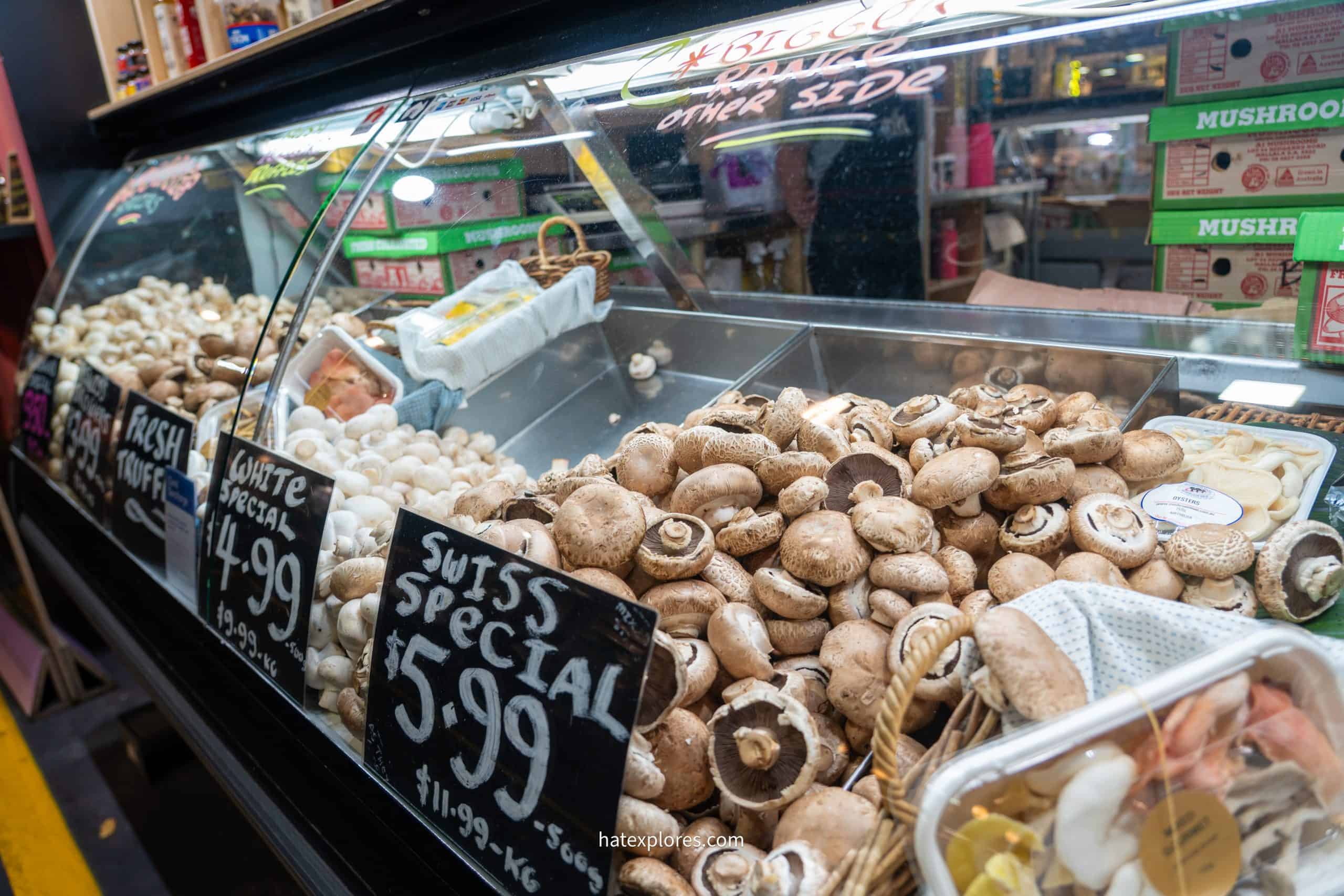 Close-up of a mushroom stall at Adelaide Central Market with signs for truffles, white mushrooms, and Swiss specials.