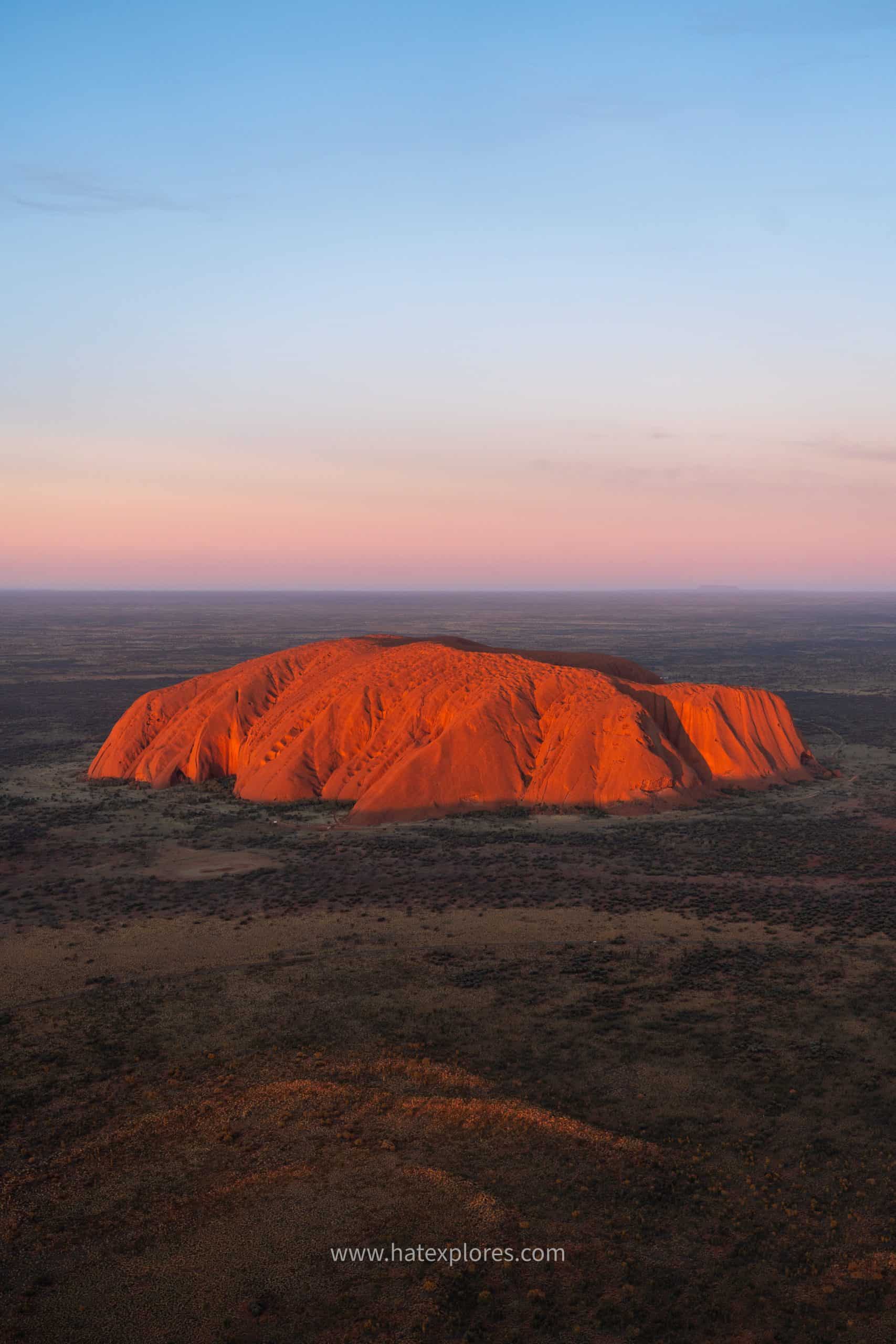 Stunning aerial shot of Uluru at sunset, glowing red in the heart of the Northern Territory – highlight of the best Uluru tour adventure.

