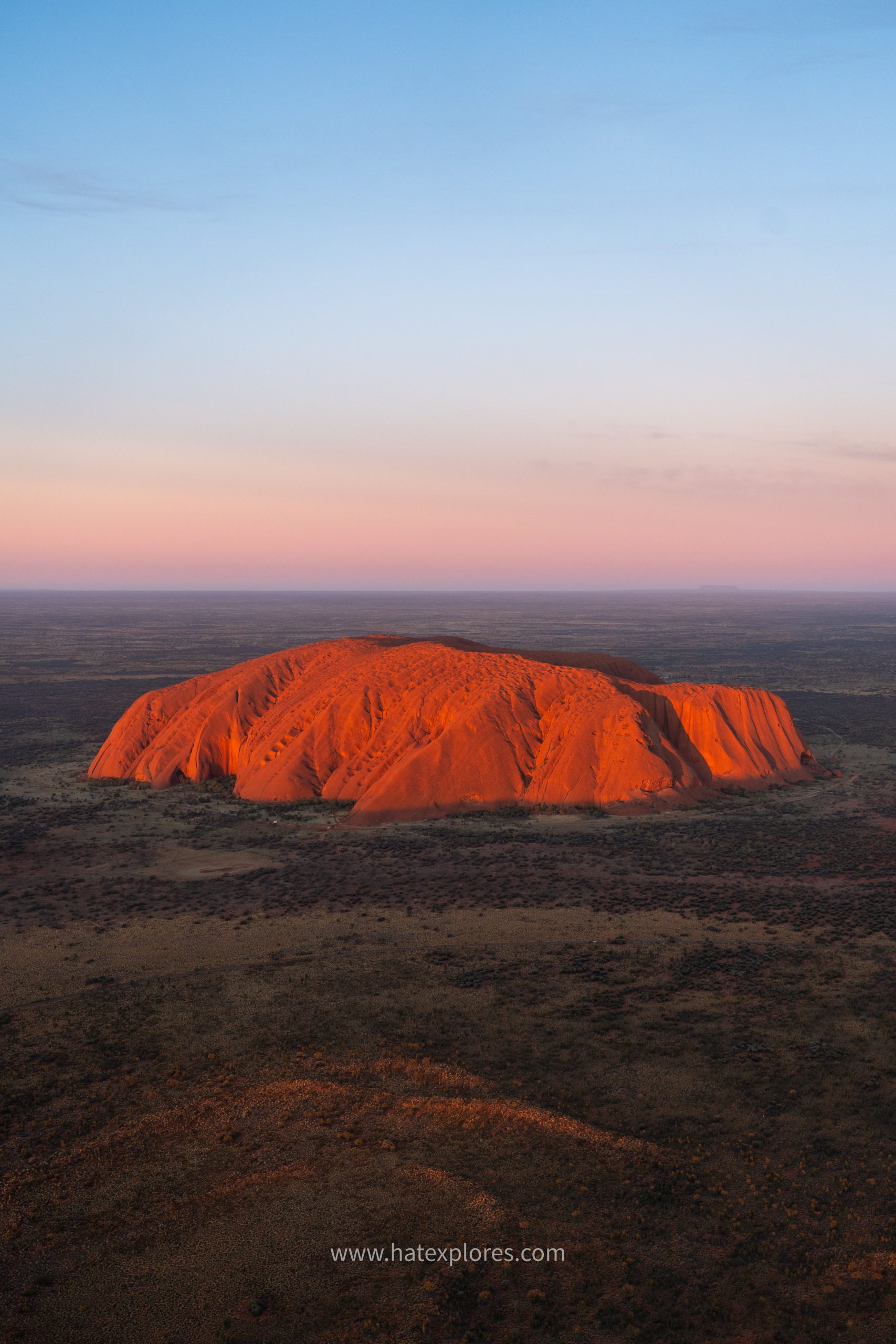 Stunning aerial shot of Uluru at sunset, glowing red in the heart of the Northern Territory – highlight of the best Uluru tour adventure.

