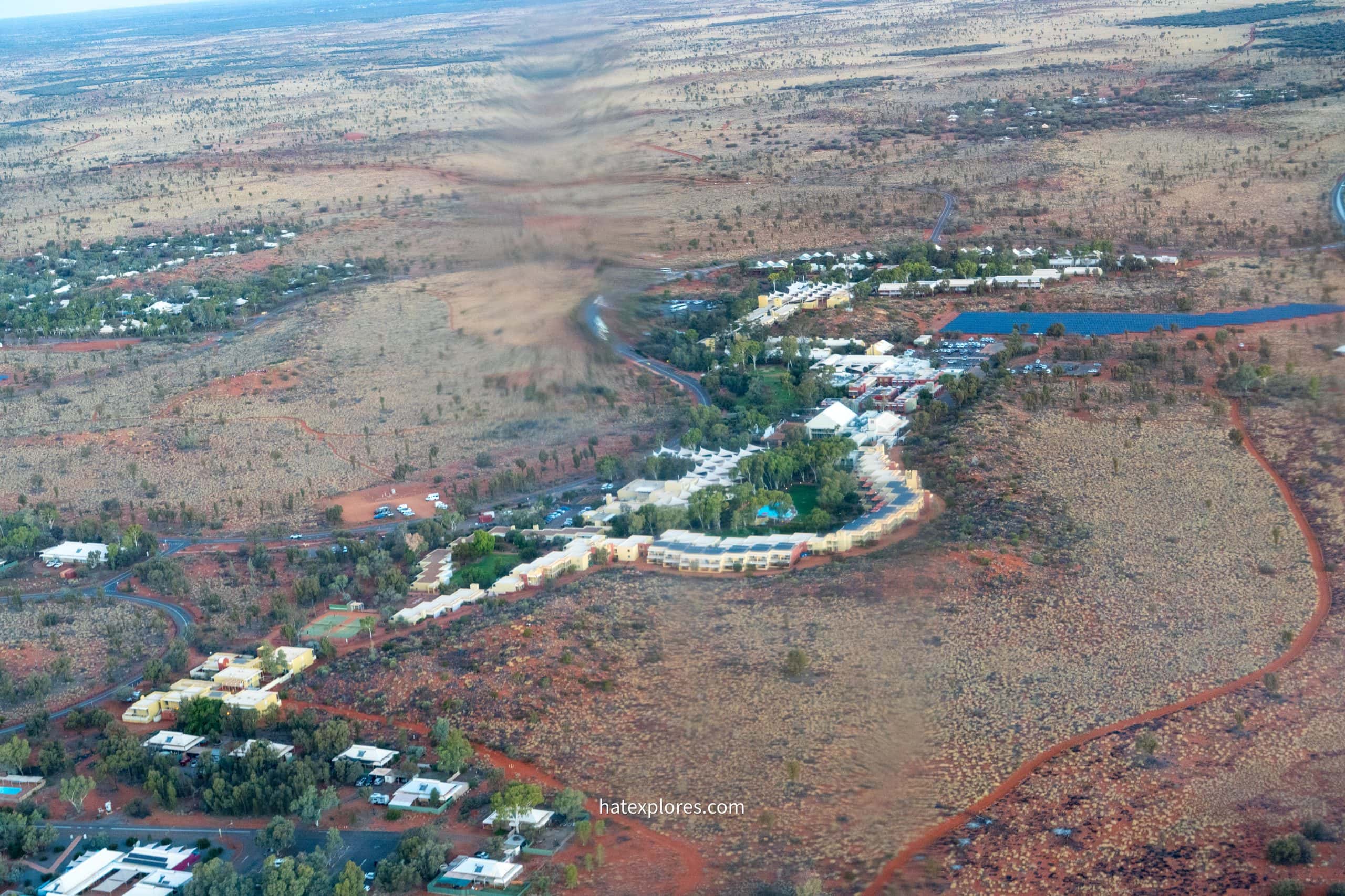 Aerial view of the Ayers Rock Resort accommodations surrounded by the vast red desert landscape, perfect base for the best Uluru helicopter tour experience!