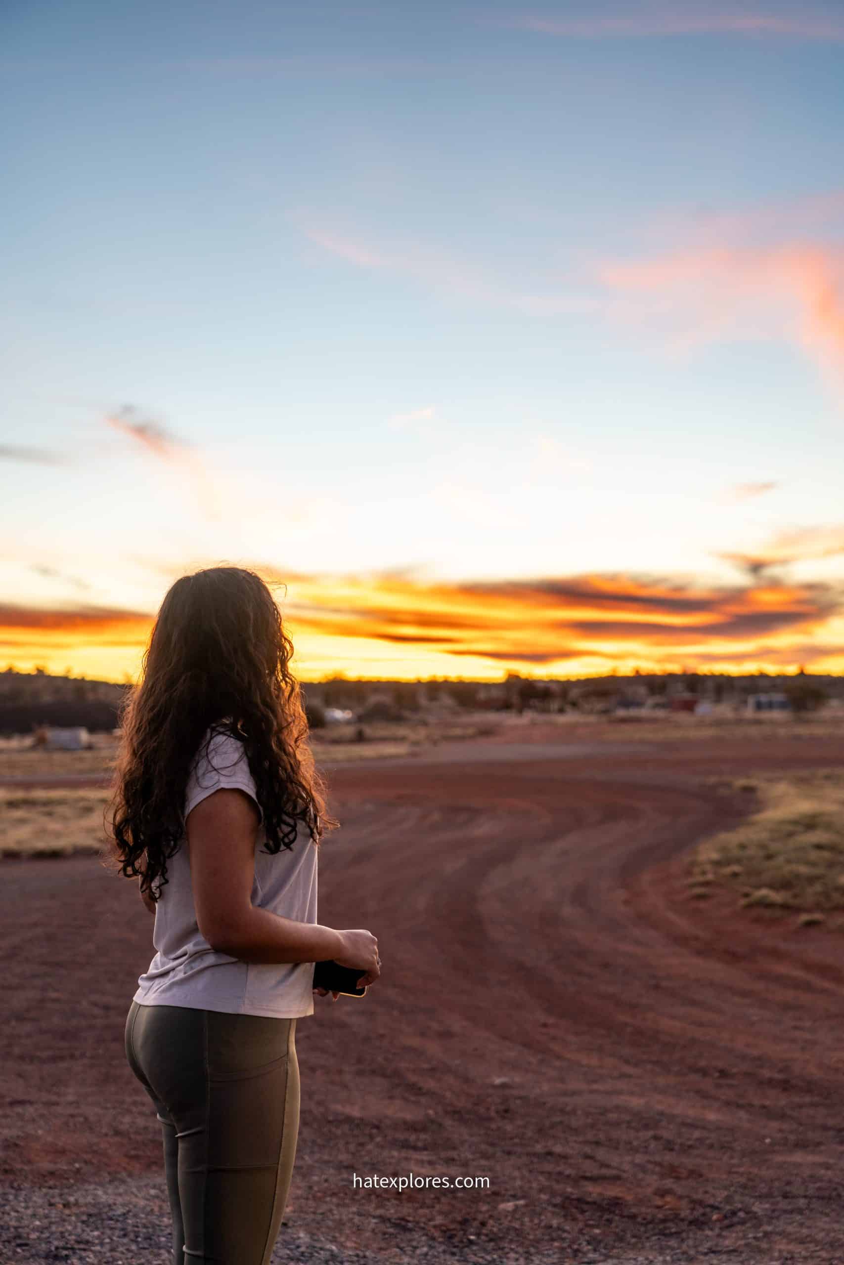 A girl is looking over the golden hued sky in Yulara.