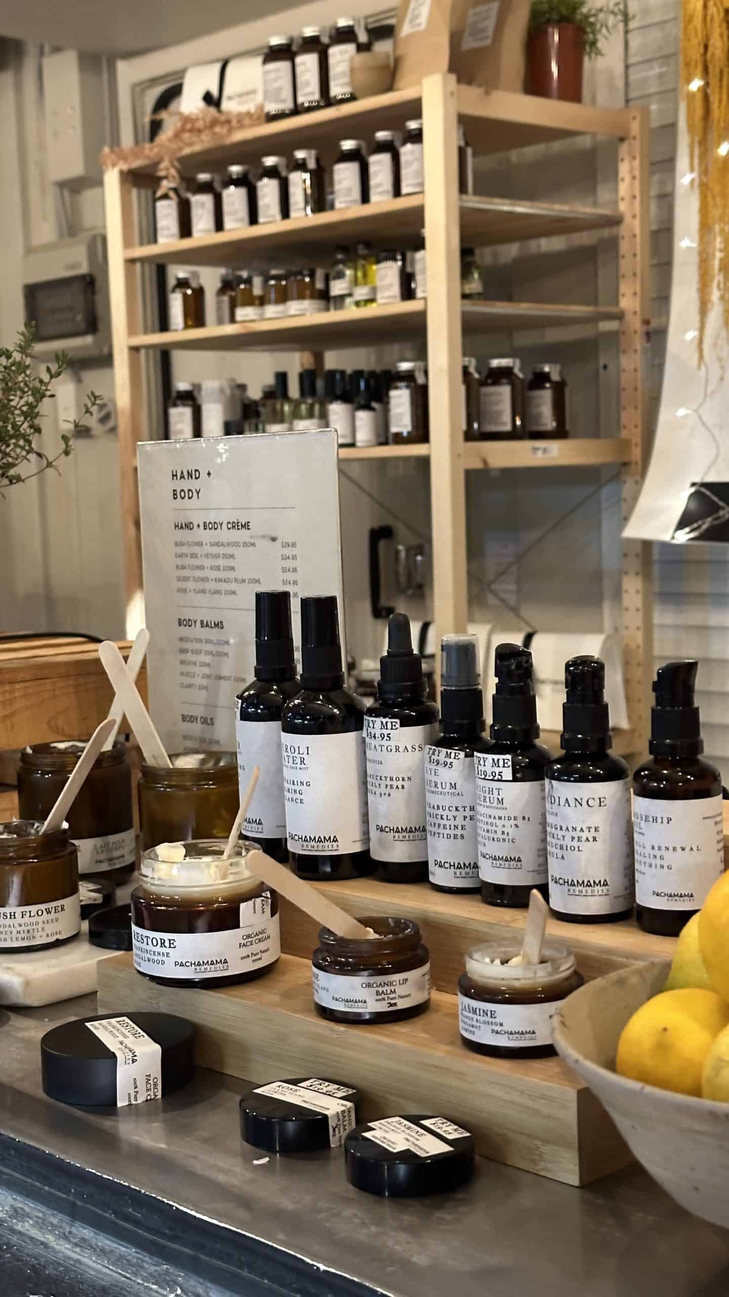 Close-up of a skincare stall at The Loco Market in Sydney, featuring a rustic wooden shelf filled with handcrafted products from Pachamama Remedies, including organic face cream, body oils, and lip balm—highlighting the wellness finds at winter markets in Sydney.
