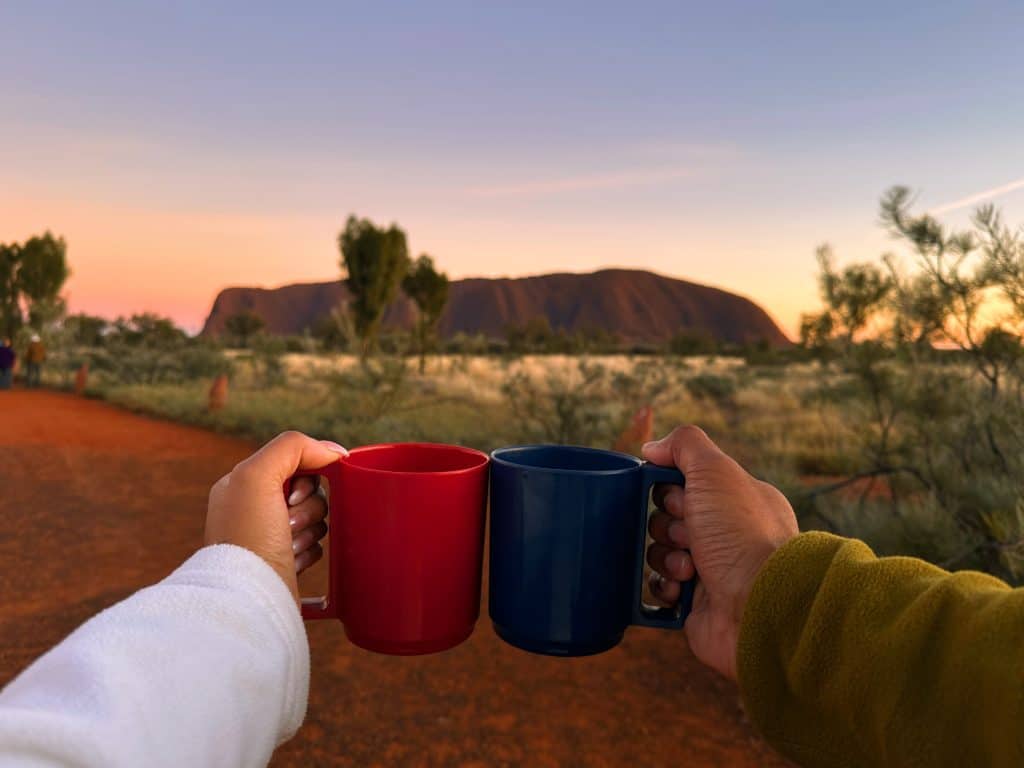 enjoying the vibrant colors of the sky during sunset at Uluru.